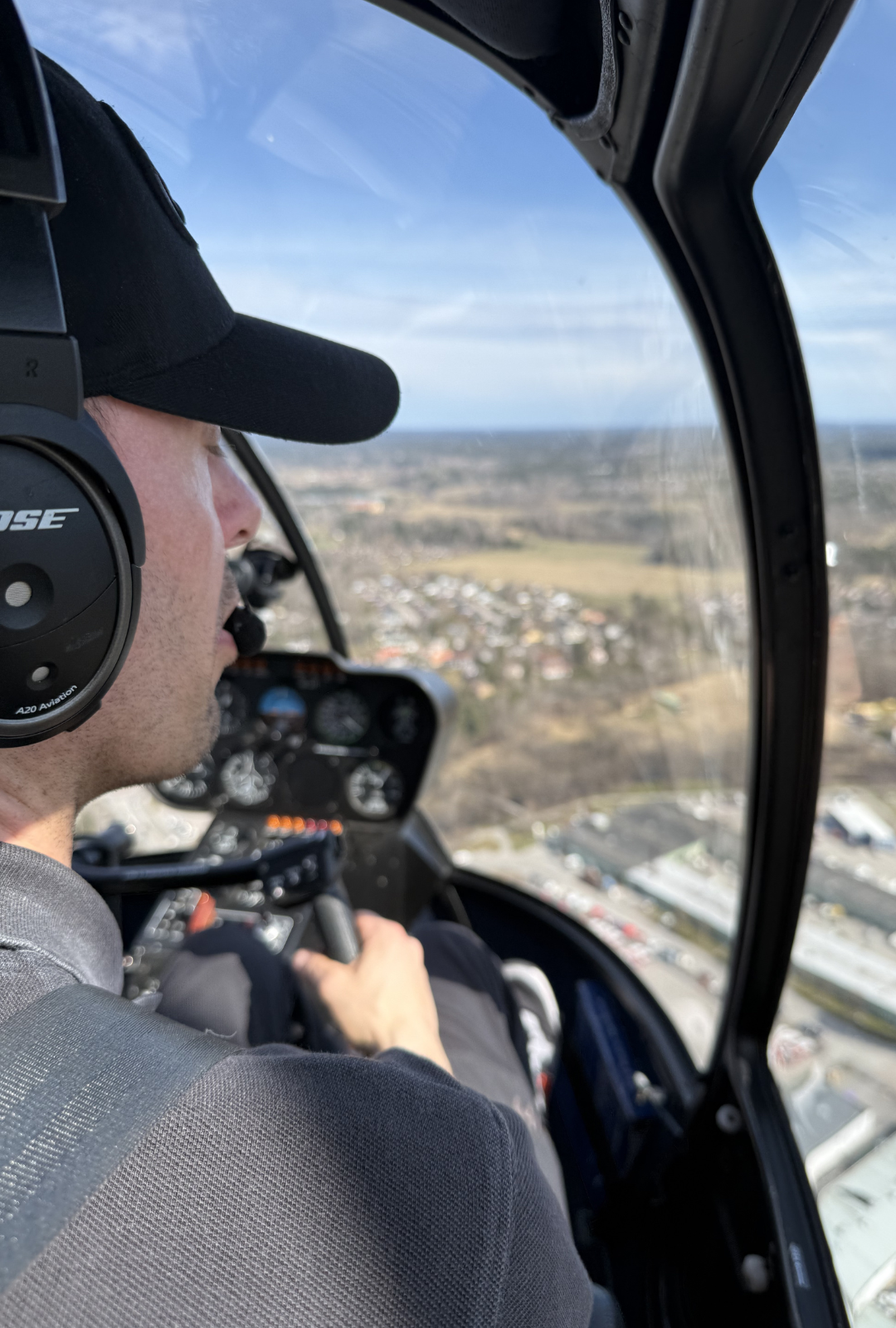 Pilot vid spakarna i Robinson R44 över Stockholm