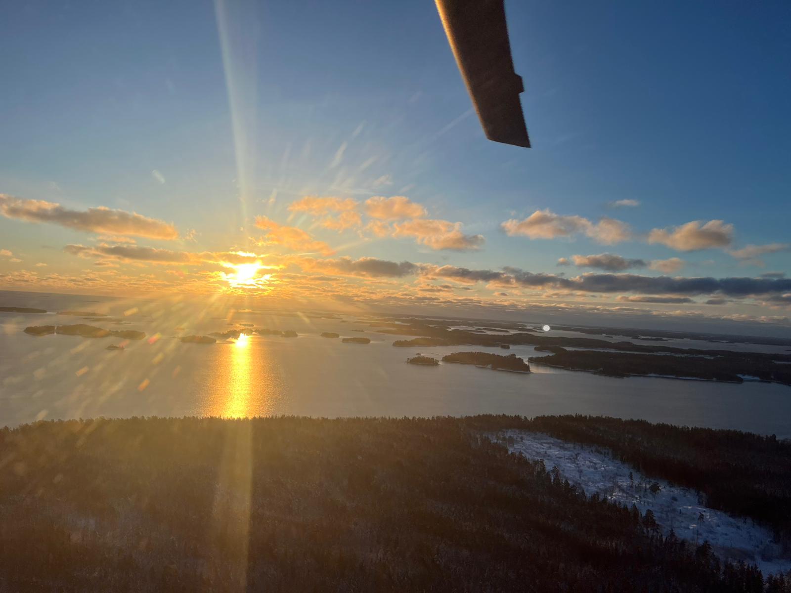 Solnedgång över snötäckt skärgård sett från helikoptern