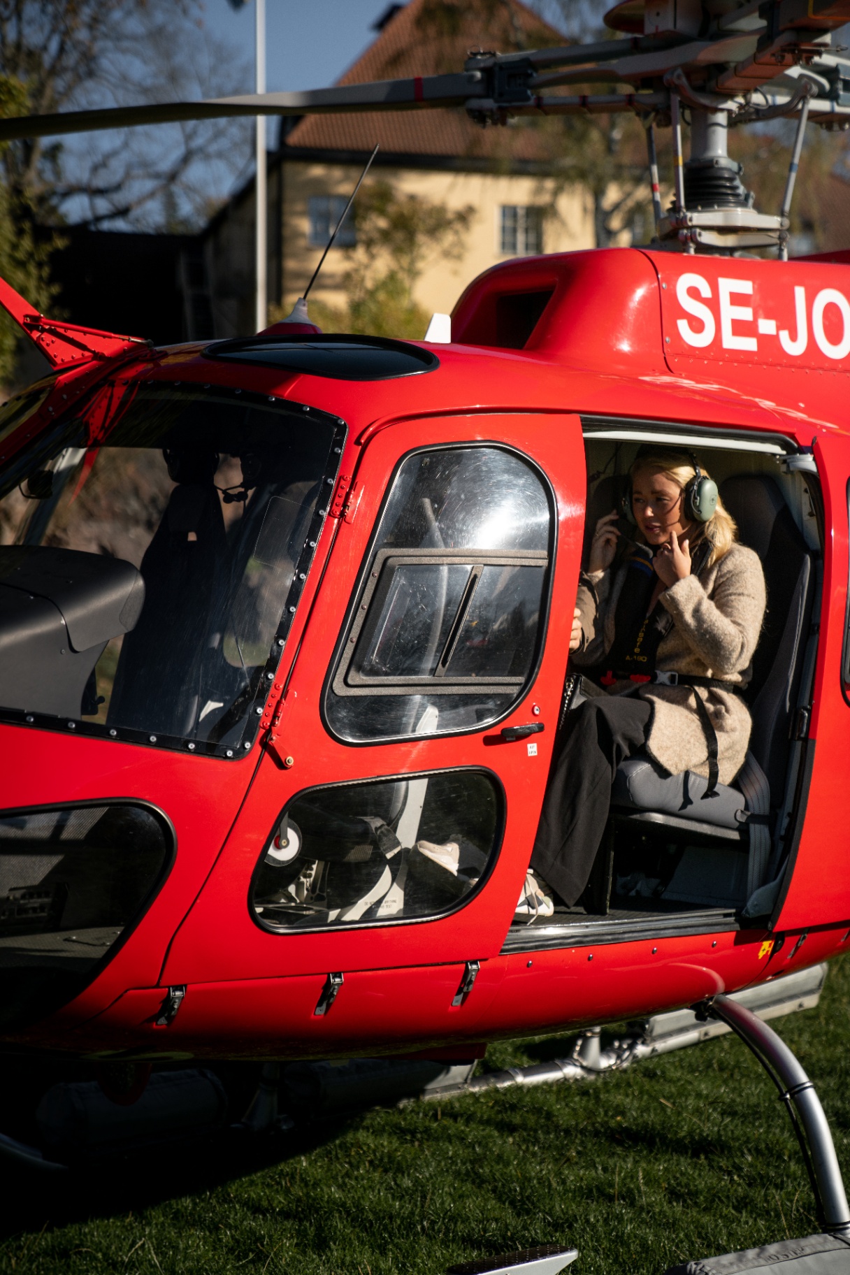 Kvinna sätter på sig headset i röd helikopter inför flygning
