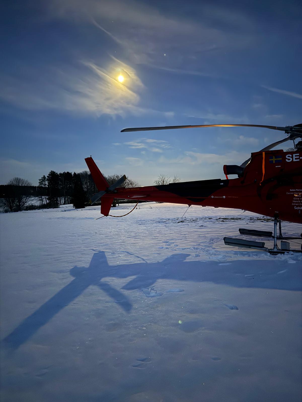 Röd helikopter i snölandskap under månljus