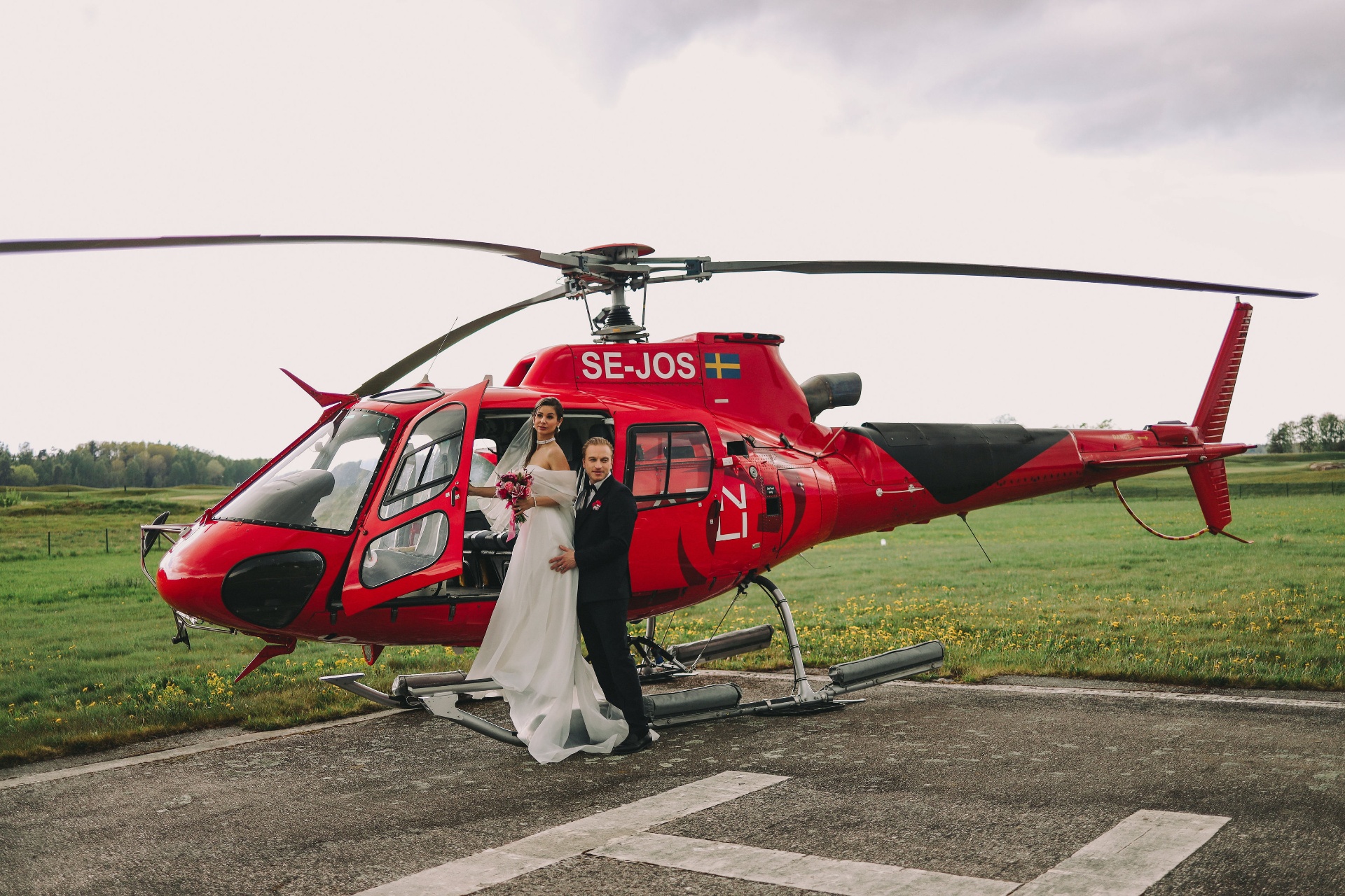 Brudpar Karyna och Ludvig vid röd helikopter SE-JOS