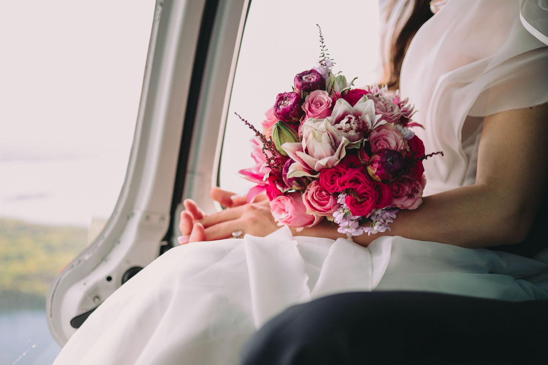 Brudens brudbukett med rosa och röda rosor ombord i helikoptern